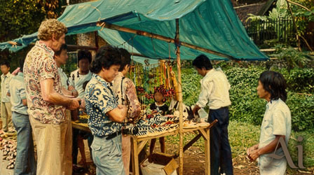 Group of people browsing handmade crafts at a shaded outdoor stall in Bogor, Indonesia.